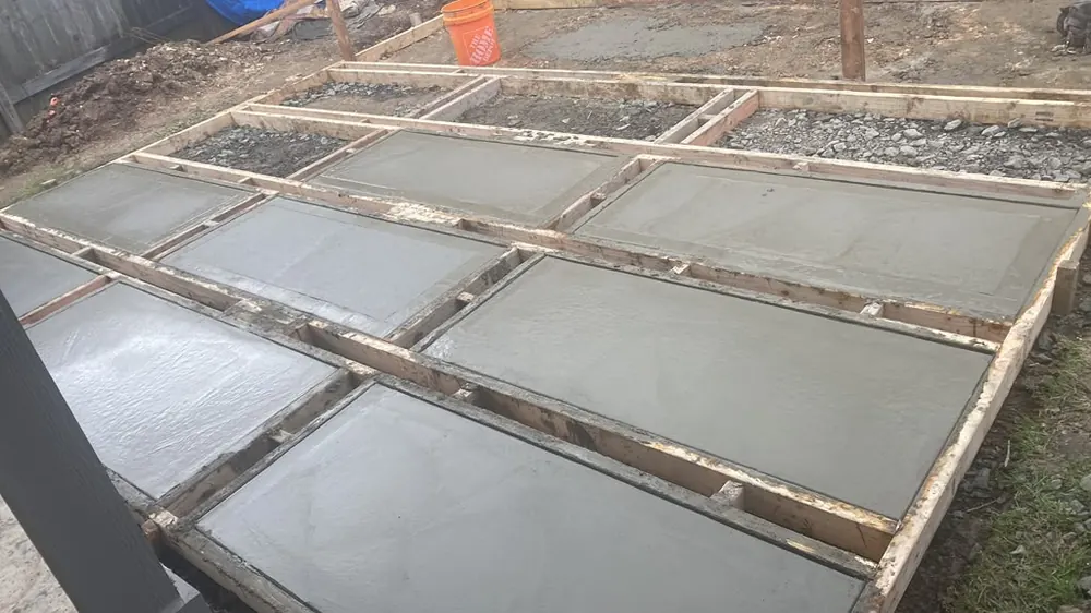 Fresh concrete pads poured into timber forms