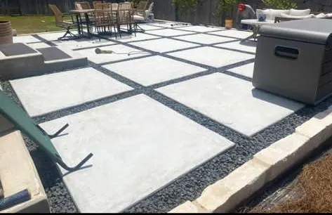Concrete pad patio with black gravel joints and a dining set