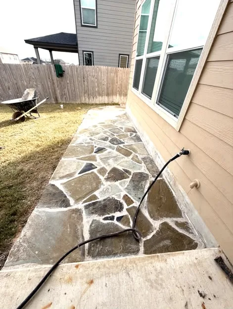 Flagstone side-yard walkway along a house with a cedar fence behind